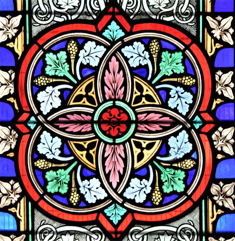 Detail from the East window stained glass, showing an interlocking pattern in red, blue and yellow, with pink flowers and green leaves